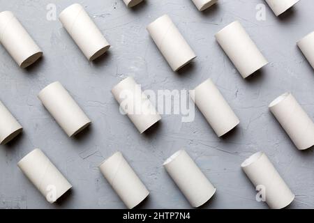 Leere Toilettenpapierrolle auf farbigem Hintergrund. Recycelbares Papierrohr mit Metallstopfende aus Kraftpapier oder Karton. Stockfoto