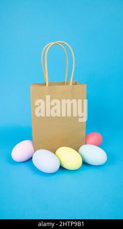Ostern, Papiertüte, Geschenk und Eier sind einfarbig, mehrfarbig auf blauem Hintergrund Stockfoto