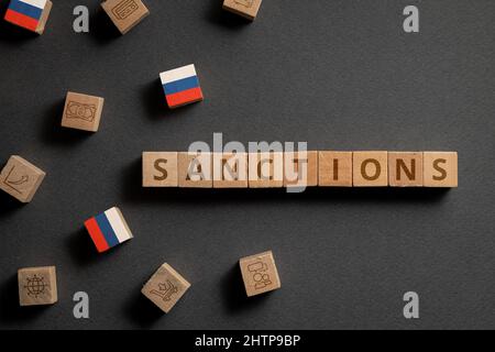 Holzwürfel mit Finanz-Ikonen, russischer Flagge und Sanktionen. Konzept zu Sanktionen in Russland Stockfoto