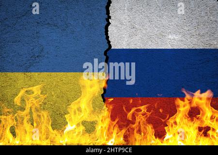 Flaggen der Ukraine und Russlands im Krieg auf der rissigen Wand hinter den Flammen Stockfoto