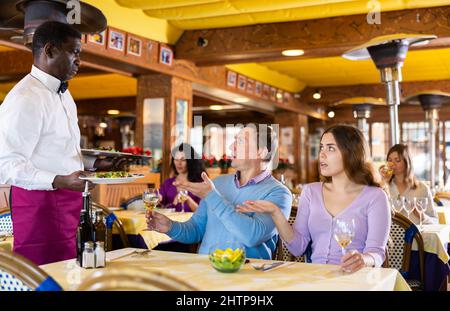 Unzufriedener Gast, der mit dem Kellner in Konflikt steht Stockfoto