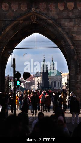 Die Türme der historischen Monumente der Mala Strana Prag durch das Tor zur Karlsbrücke über die Moldau gesehen. Verschwommene Menschen Stockfoto