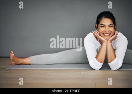 Yoga setzte mir dieses Lächeln ins Gesicht. Porträt einer attraktiven jungen Frau, die die Splits in ihrer Yoga-Routine macht. Stockfoto