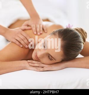 Entspannt durch magische Hände. Kurzer Schuss einer wunderschönen jungen Frau, die eine Massage genießt. Stockfoto