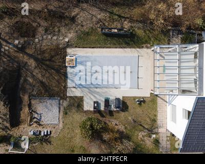 Drohnenflug über einen überdachten Pool mit einer Plane, die in einem Garten noch im Bau ist Stockfoto