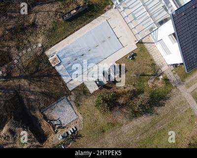 Drohnenflug über einen überdachten Pool mit einer Plane, die in einem Garten noch im Bau ist Stockfoto