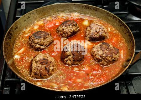 Fleischbällchen vom Rind, die in einer Pfanne mit einem Ragu Tomatensauce köcheln Stockfoto