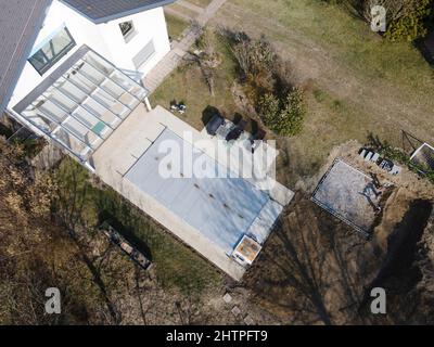 Drohnenflug über einen überdachten Pool mit einer Plane, die in einem Garten noch im Bau ist Stockfoto