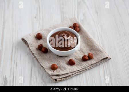 Hausgemachte Schokolade Haselnuss verteilt in einer Schüssel auf einer weißen Holzoberfläche, Seitenansicht. Stockfoto