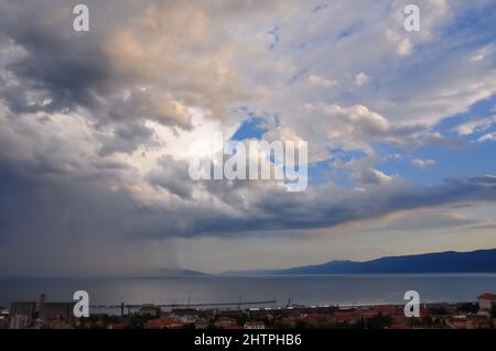 Stürmischer Himmel über Meer und Stadt. Rijeka Bucht und Regen kommen. Regenvorhang über dem Meer in der Bucht von Rijeka.dramatische Landschaft des stürmischen Himmels über der kleinen Küstenstadt Stockfoto