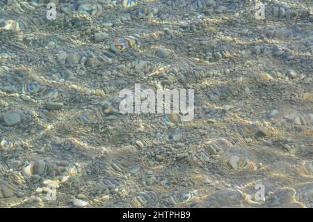 Klare Meerwasserstruktur. Unterwasser Meeressteine, Oberfläche Mit Wellen Und Wellen, Schönes Muster Transparentes Klares Wasser. Kieselsteine am Strand. Stockfoto