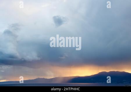 Regenwolken über der Kvarner Bucht und den Bergen in Rijeka, Kroatien. Wolken, Himmel, Wasser und Berge über dem blau schimmernden Wasser. Stockfoto