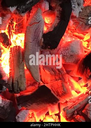 Schwelende Holzkohle in der Nacht auf dem Grill.Hintergrund von einem Feuer, Feuerholz und Kohlen.Nahaufnahme Textur von brennender Holzkohle Stockfoto