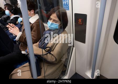 Menschen mit Gesichtsmasken in einem Londoner U-Bahn-Zug am 16.. Februar 2022 in London, Großbritannien. Zwar ist das obligatorische Tragen von Gesichtsbezügen an öffentlichen Orten nicht mehr vorgeschrieben, doch der Rat des TfL Transport for London zum Gesichtsbedeckung lautet derzeit wie folgt: Sie müssen eine Gesichtsbedeckung über Nase und Mund, auf dem Transport for London-Netz, in Bahnhöfen und während der gesamten Reise tragen. Wenn Sie dies nicht tun und nicht von der Ausnahmeregelung befreit sind, könnte Ihnen die Einreise verweigert, Ihnen die Reise verweigert oder Ihnen gesagt werden, unsere Bahnhöfe und Dienstleistungen zu verlassen. Stockfoto