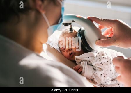 Arzt untersucht Neugeborenes im Krankenhauszimmer. Stockfoto