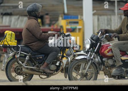 Schwarzer Afrikanischer Mann mit Helm auf einem Motorrad Stockfoto