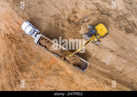 Bagger und Lastwagen arbeiten an den Aushubarbeiten einer Straße, Erde bewegen Stockfoto