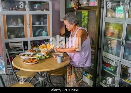 Asiatische alte Großmutter, die frisch gekochte traditionelle thailändische Gerichte serviert Stockfoto