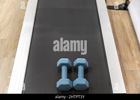 Ein Laufband mit blauen Handgewichten auf ihm bereit für eine Übung oder Workout-Routine Stockfoto