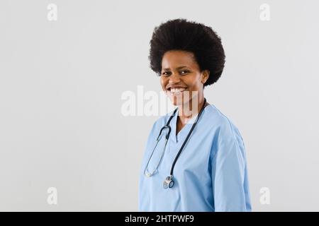 Porträt einer glücklichen afroamerikanischen mittleren erwachsenen Ärztin vor weißem Hintergrund, Kopierraum Stockfoto