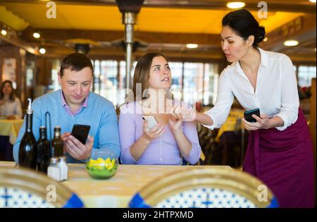 Paar mit Smartphones, um Essen im Restaurant zu bestellen Stockfoto
