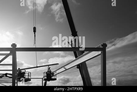 Moderner Supermarkt, der von Arbeitern gebaut wird, die Stahlgerüste mit großen Maschinen an einem schönen Tag in Beverley, Großbritannien, errichten. Stockfoto