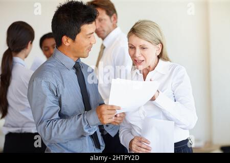 Hilfe aus einem erfahrenen Auge tut nie weh. Zwei Geschäftsleute diskutieren ein Dokument. Stockfoto