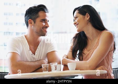 Glücklich im Bistro. Aufnahme eines jungen Paares, das zusammen eine Tasse Kaffee schnappte. Stockfoto