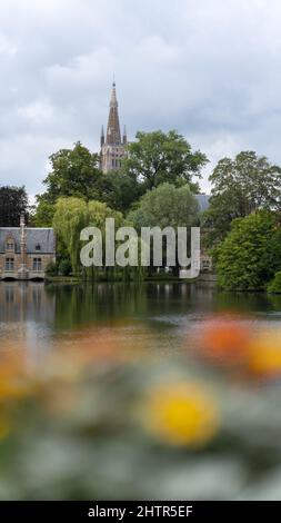Vertikale Aufnahme eines Burgturms hinter den Bäumen am Seeufer Stockfoto