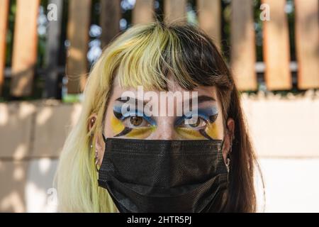 Bangkok, Thailand. 02. März 2022. Während einer Demonstration gegen den russischen Angriff auf die Ukraine vor der russischen Botschaft in Bangkok wird ein Protestler mit Augen-Make-up in blau-gelben, ukrainischen Farben gesehen. (Foto von Varuth Pongsapipatt/SOPA Images/Sipa USA) Quelle: SIPA USA/Alamy Live News Stockfoto