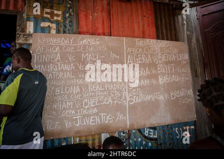 Freetown, Sierra Leone. 12. Januar 2022. Eine Tafel in einem 'Kino' in Freetown wirbt für die Zeiten der Fußballspiele, die sie vorführen werden.Sierra Leone qualifizierte sich 2022 zum ersten Mal seit 26 Jahren für den Afrika-Cup der Nationen, Vielen lokalen Fußballspielern Hoffnung zu geben, dass sie künftig mehr internationale Chancen erhalten werden. Kredit: SOPA Images Limited/Alamy Live Nachrichten Stockfoto