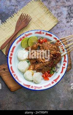 Indonesisches berühmtes Essen: Sate ayam (Chicken Satay), serviert mit Erdnusssauce und Reiskuchen oder Lontong Stockfoto