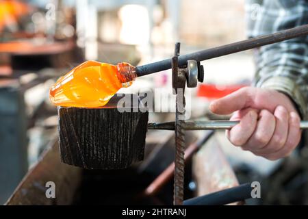 Glas bläst die Hände des Handwerkers, der mit geschmolzenem Glas arbeitet, traditionelles Handwerk Stockfoto