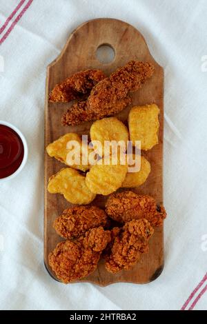 Leckeres Fastfood: Hühnchen-Nuggets, Flügel und Tender mit Ketchup, Draufsicht. Über Kopf, von oben, flach liegend. Stockfoto