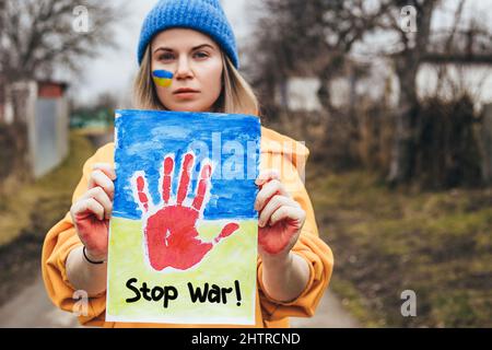 Porträt einer jungen schönen Frau mit Blumen und ukrainischer Flagge. Beenden Sie den Krieg in der Ukraine. Russland beendet den Krieg. Stockfoto