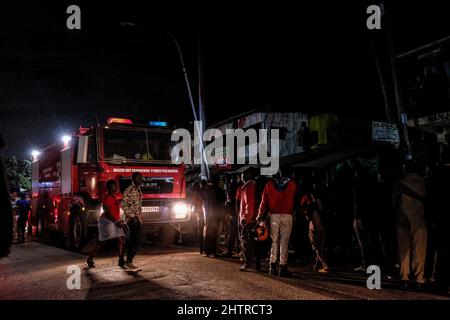 Nairobi, Kenia. 1. März 2022. Bewohner beobachten aus der Ferne, wie Feuerwehrleute in den Slums von Kibera kämpfen, um ein Feuer zu löschen. Am 1.. März 2022. Die Bewohner der Slums von Kibera erlebten einen weiteren Verlust, als sie von einem Feuer, das spät in der Nacht auftrat und zwanzig Häuser niederwüste, nicht bemerkt wurden, und die meisten Einheimischen obdachlos blieben und sich an nichts wenden konnten. Der Ausbruch des Feuers war auf verworrene Drähte aus illegalen elektrischen Verbindungen zurückzuführen. (Bild: © Donwilson Odhiambo/ZUMA Press Wire) Stockfoto