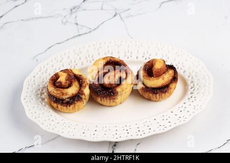 Wunderschöne frische Zimtbrötchen aus nächster Nähe auf dem weißen Tisch. Duftende hausgemachte Kuchen, Konzept für White Bakery Stockfoto