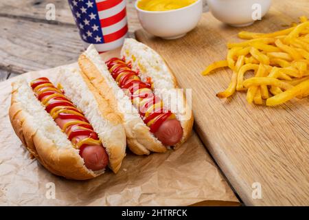 Hot Dogs mit Tomate und musterte Sauce serviert mit pommes frites und Getränk am Tisch serviert Stockfoto