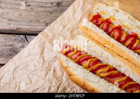 Nahaufnahme von Hotdogs mit mustert und Tomatensauce auf braunem Wachspapier am Tisch Stockfoto