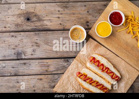 Blick von oben auf Hot Dogs mit pommes Frites und Saucen bei einem Getränk auf dem Tisch Stockfoto