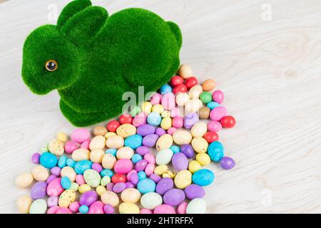 High-Angle-Ansicht von künstlichem Moos Hase mit bunten Süßigkeiten ostereier auf dem Tisch Stockfoto