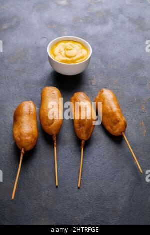 Nahaufnahme eines Maishundes mit Senfsauce in einer Schüssel auf dem Tisch Stockfoto