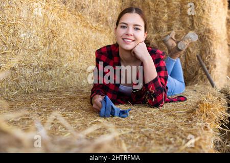 Frau, die auf dem Bauernhof bei Strohhalmen posiert Stockfoto