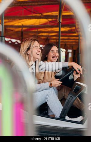 Zwei junge Frauen, die Spaß haben, während sie ein Autoscooter fahren Stockfoto
