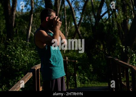 Junger Mann fotografiert in der Natur mit einer Vintage-Kamera Stockfoto