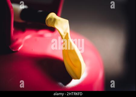 Selektiver Fokus auf den Rand eines aufblasbaren Ballons, der an einem Heliumbehälter befestigt ist. Stockfoto