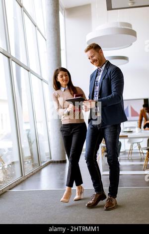 Junge Unternehmer gehen zusammen und nutzen digitale Tablets im modernen Büro Stockfoto