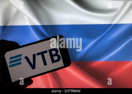 Rheinbach, Deutschland 2. März 2022, das Markenlogo der russischen "VTB Bank" auf dem Display eines Smartphones vor einer russischen Flagge Stockfoto