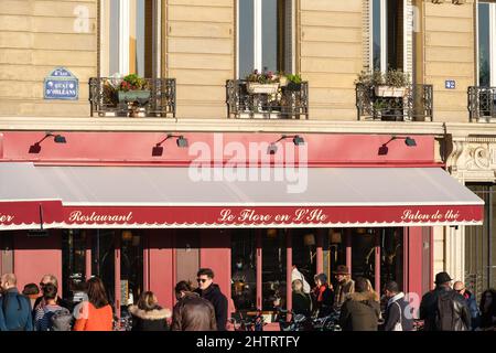 Paris, Frankreich - 27. Februar 2022 : Touristen, die an einem sonnigen Tag in einem berühmten Pariser Restaurant Platz nehmen möchten Stockfoto