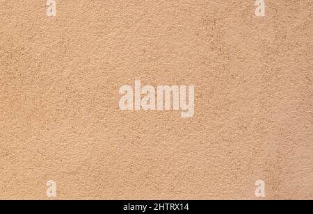 Rauh körnig bemalter sandfarbener Putz Wand Hintergrund. Stockfoto